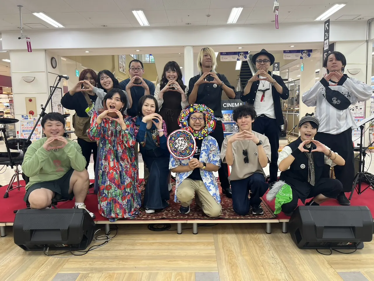 ステージの上で、両手でハートの形をつくる出演者のみなさんの集合写真